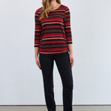 Woman wearing a red and black striped top with black pants against a white background