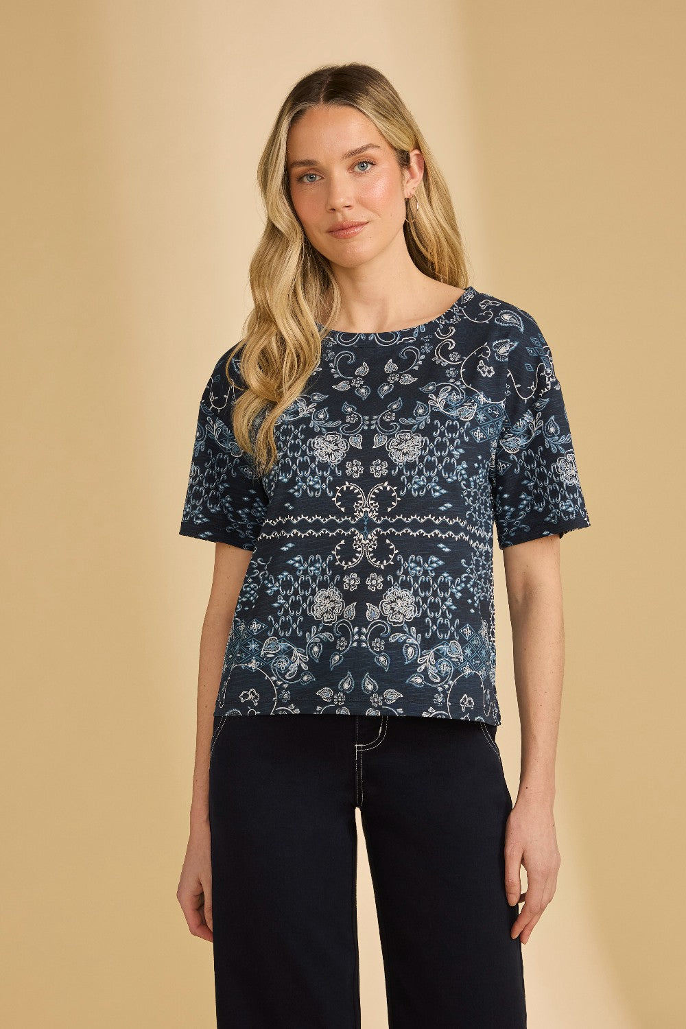 Woman wearing a navy blue patterned top against a beige background