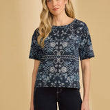 Woman wearing a navy blue patterned top against a beige background