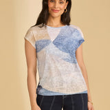 Woman wearing a patterned top and dark shorts on a beige background