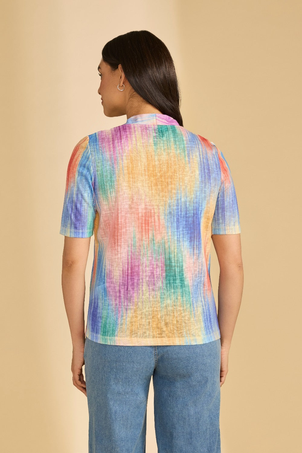 Person wearing a colorful shirt against a beige background