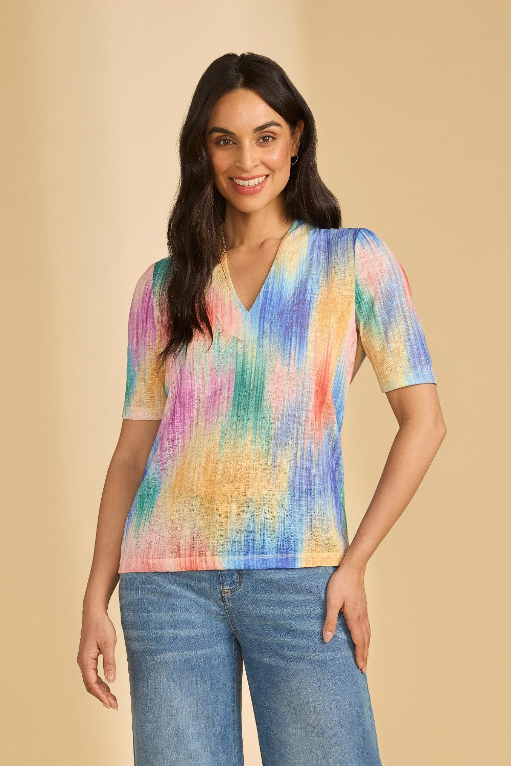 Woman wearing a colorful shirt and jeans on a beige background