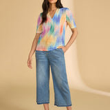 Woman wearing a colorful shirt and blue jeans on a beige background