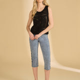 Woman wearing a black sleeveless top and blue jeans on a beige background