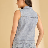Woman wearing a sleeveless denim top and jeans on a beige background