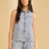 Woman wearing a sleeveless denim top and pants on a beige background
