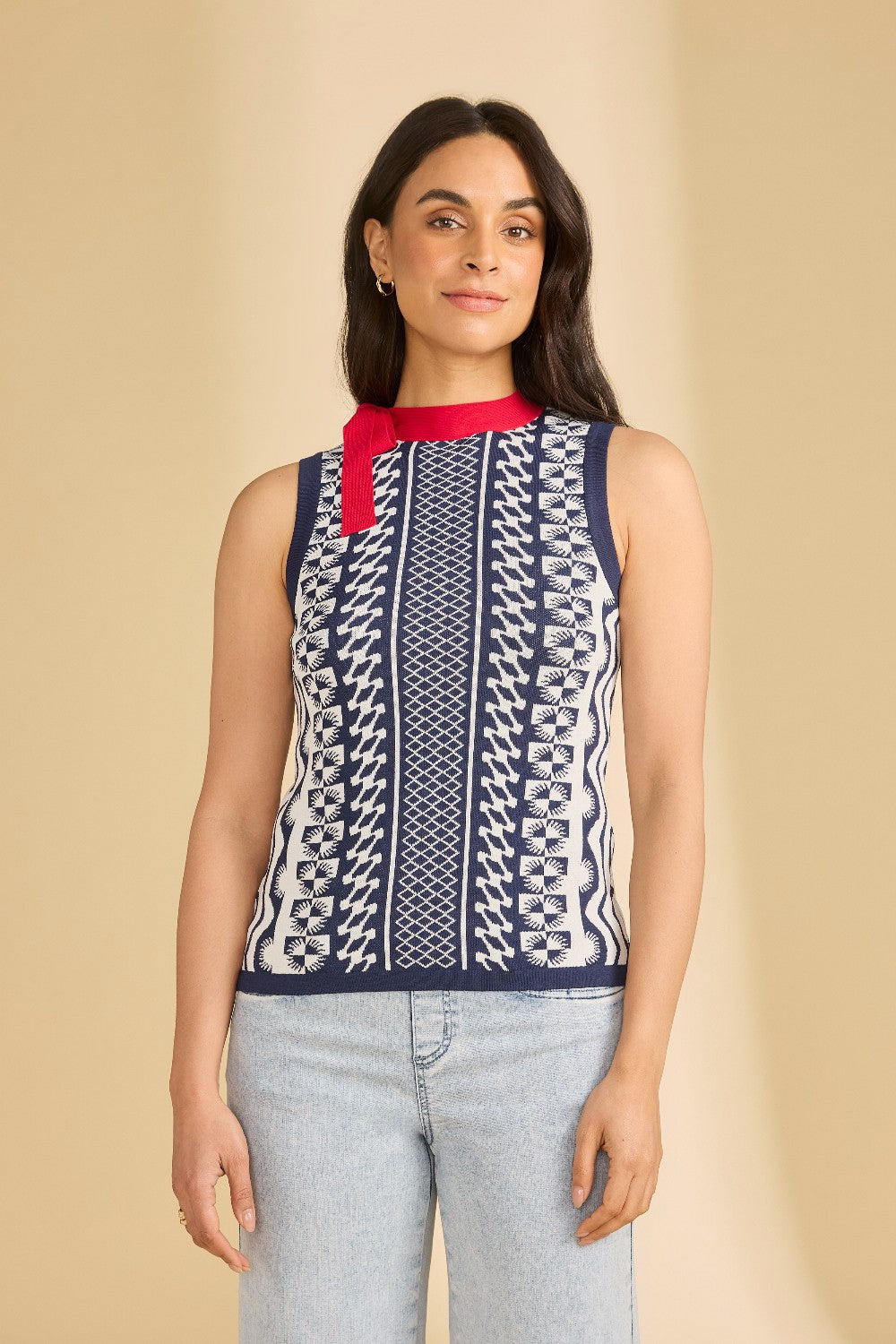 Woman wearing a sleeveless patterned top with a red collar against a beige background