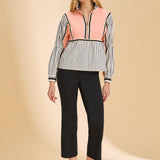 Woman wearing a colorful striped shirt and black pants on a beige background