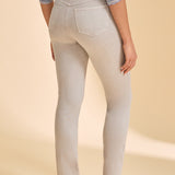 Person wearing grey jeans with a multi coloured shirt against a beige background