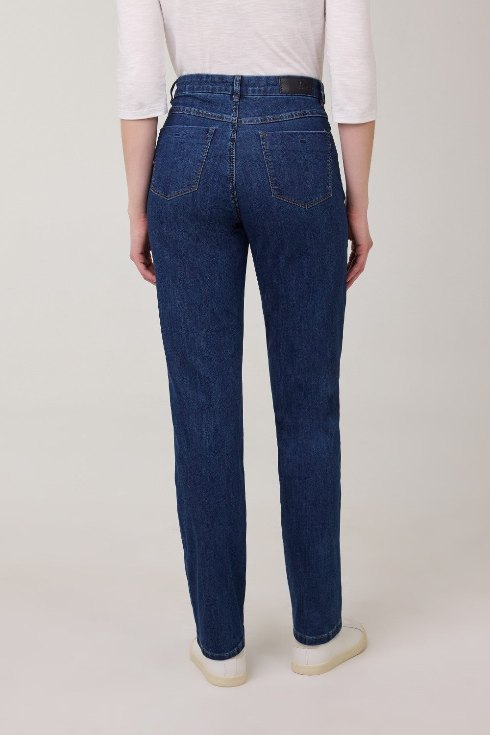 Person wearing blue jeans and a white shirt on a plain background