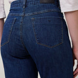 Person wearing blue jeans with a plain background