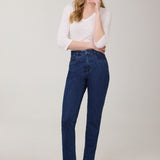 Woman wearing blue jeans and a white top on a plain background