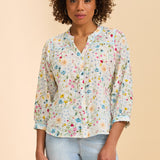 Woman wearing a floral blouse and light blue jeans on a beige background