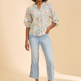 Woman wearing a floral blouse and light blue jeans on a beige background