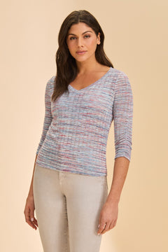 Woman wearing a multicolored top and beige pants on a beige background