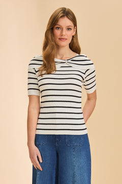 Person wearing black and white striped short sleeve sweater with denim against beige background