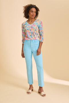 Woman wearing a colorful top and light blue jeans on a beige background