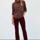 Woman wearing a brown turtleneck and pants against a white background