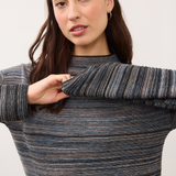 Closeup of a woman wearing a blue striped sweater on a light background.