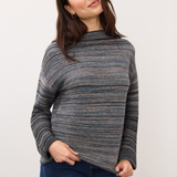 Woman wearing a blue striped sweater with blue jeans on a light background.