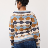 Woman, shown from behind, modelling a multi coloured sweater with a houndstooth printed denim photographed against a light background.