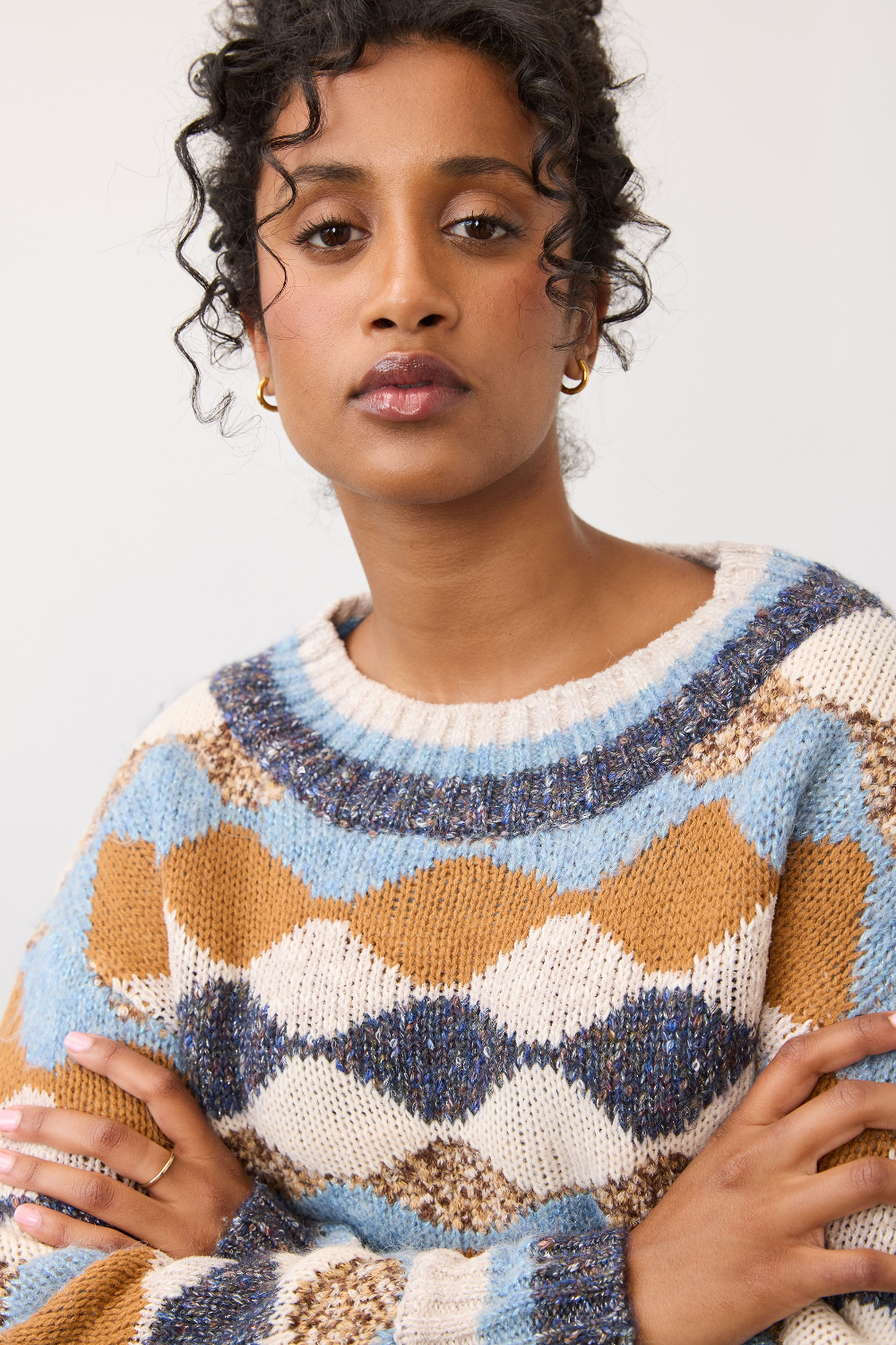 Woman modelling a multi coloured sweater photographed against a light background.