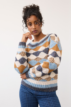 Woman modelling a multi coloured sweater with a houndstooth printed denim photographed against a light background.