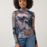 Women modelling a multi coloured mock neck top with blue jeans photographed against a light background.