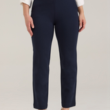 A woman modeling a white textured button-up blouse and navy cropped trousers with tan pointed-toe heels, standing against a light gray studio background.