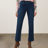 A model is shown from the waist down wearing dark blue straight-leg jeans, a pink floral long-sleeve top, and brown pointed-toe heeled ankle boots, standing against a neutral studio backdrop.