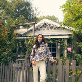 Woman standing in front of a wooden gate with greenery