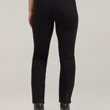 Rear view of a model wearing black high-waisted straight-leg jeans, a white top, and black high-heeled pumps with tan soles, against a light gray studio background.