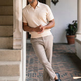 Man standing on a staircase wearing a beige shirt and light-colored pants.