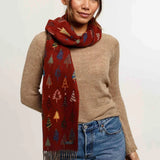 Woman wearing a patterned red scarf, beige sweater, and blue jeans on a white background