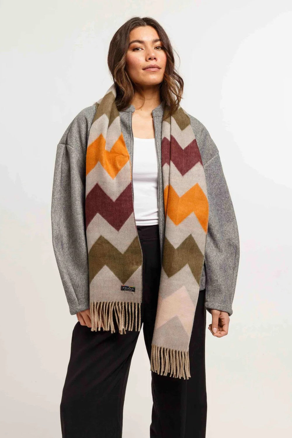 Woman wearing a colorful chevron-patterned scarf with a gray border on a white background