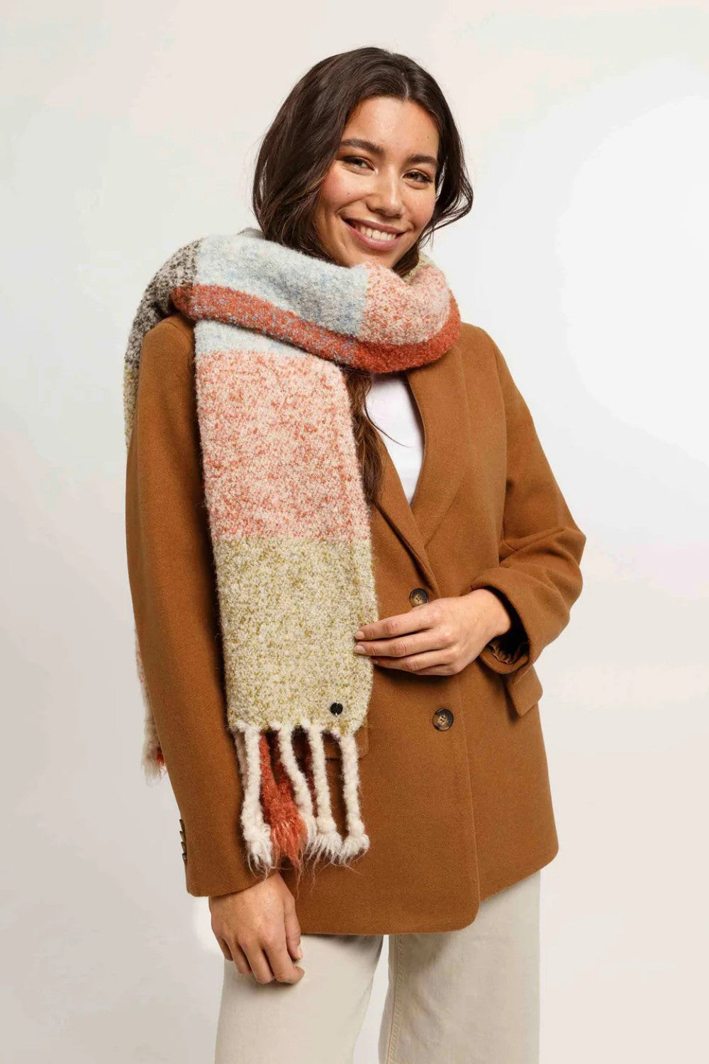 Woman wearing a brown coat and colorful scarf on a white background
