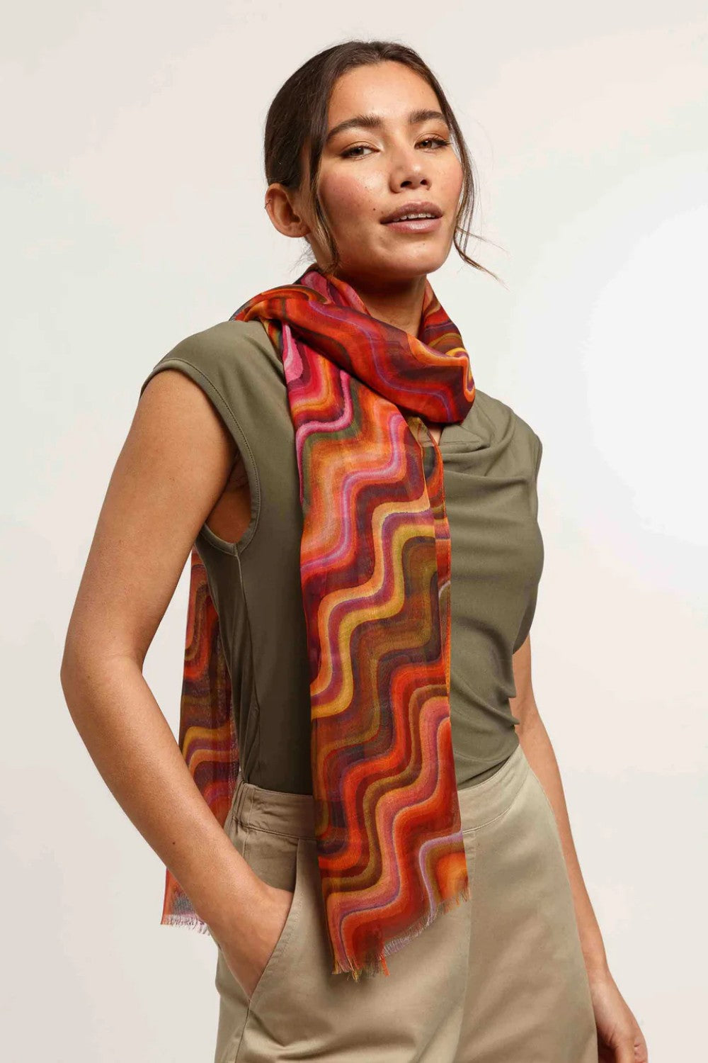 Woman wearing a colorful scarf with a plain background