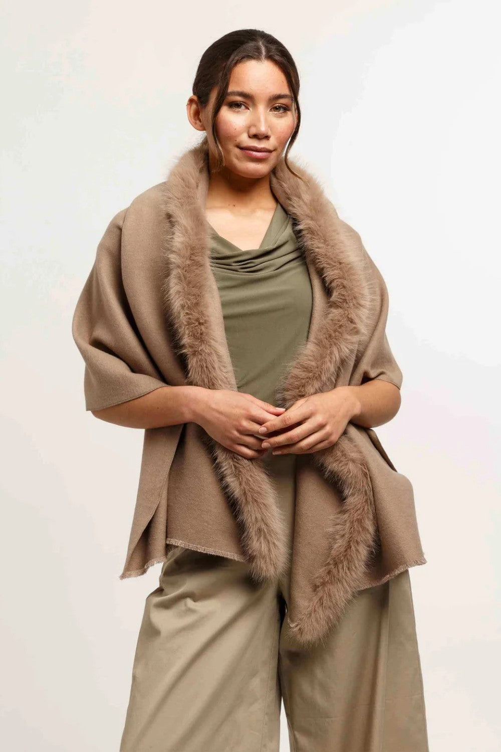 Woman wearing a brown shawl with fur trim on a white background