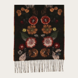 A black woven scarf with a detailed floral pattern in red, orange, yellow, and green, finished with fringe on one end, shown against a plain off-white background.