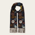 A dark navy scarf with a colorful floral pattern, finished with fringe at the ends, displayed against a solid off-white background.
