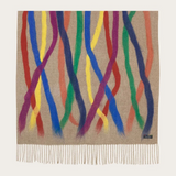 A beige based scarf with multi coloured brushstoke patterns, and fringe, photographed against a light backdrop.