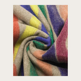 A beige based scarf with multi coloured brushstoke patterns photographed against a light backdrop.