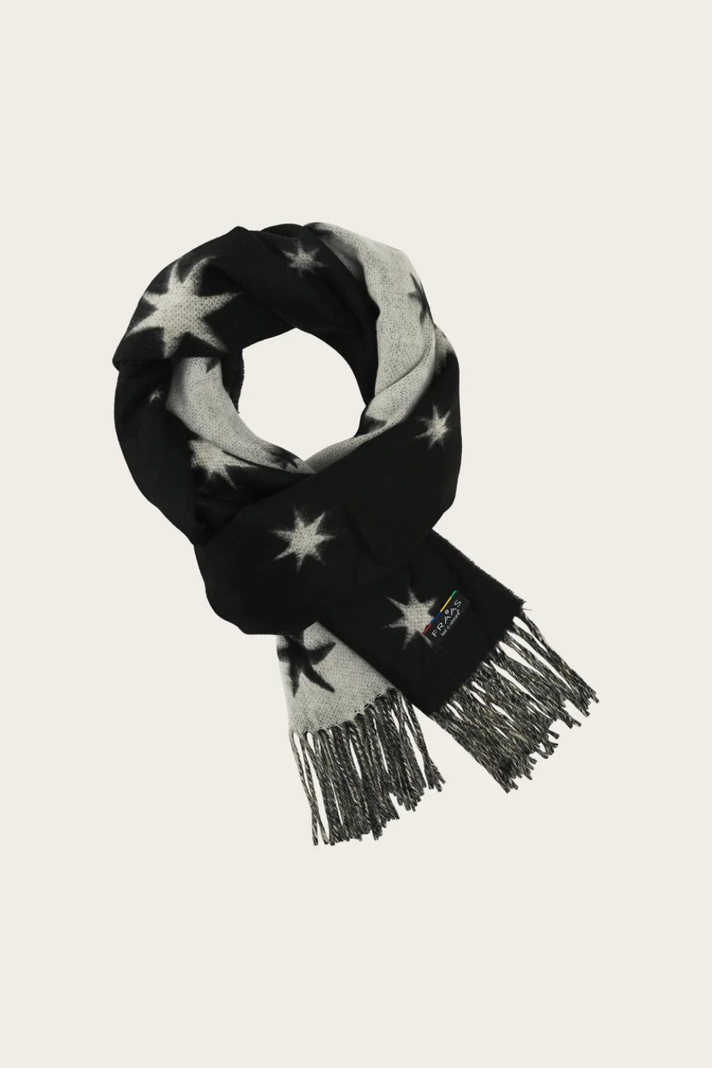 A black and white patterned scarf with star motifs and fringed ends, displayed on a light beige background.