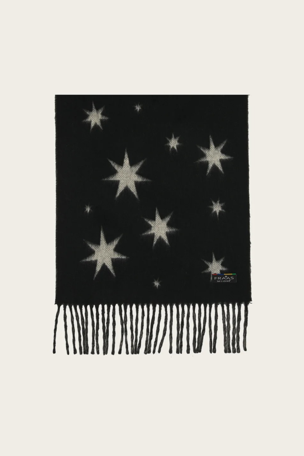 A black knit scarf with knitted star patterns in a light beige color and fringed edges, displayed flat against a light cream background.