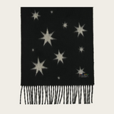 A black knit scarf with knitted star patterns in a light beige color and fringed edges, displayed flat against a light cream background.