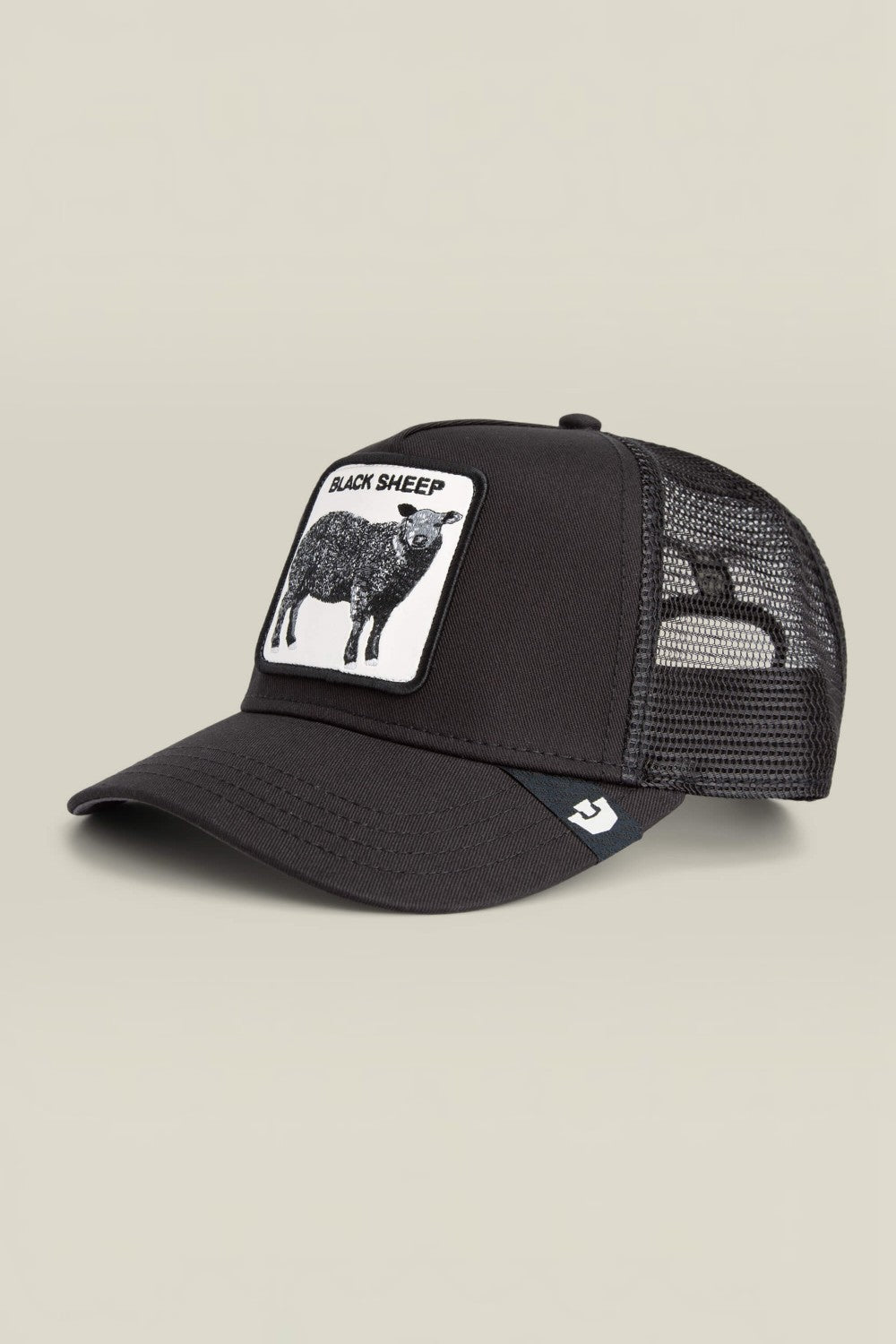 A black trucker cap with a white rectangular patch on the front featuring a black sheep illustration and the text 'BLACK SHEEP'. The back of the cap is made of black mesh, and a small white logo is visible on the side.