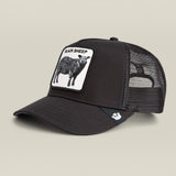 A black trucker cap with a white rectangular patch on the front featuring a black sheep illustration and the text 'BLACK SHEEP'. The back of the cap is made of black mesh, and a small white logo is visible on the side.