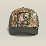 A camouflage trucker cap with a dark olive green brim and mesh back, featuring a rectangular front patch with a duck hunting illustration and the word 'Duck Hunt'.