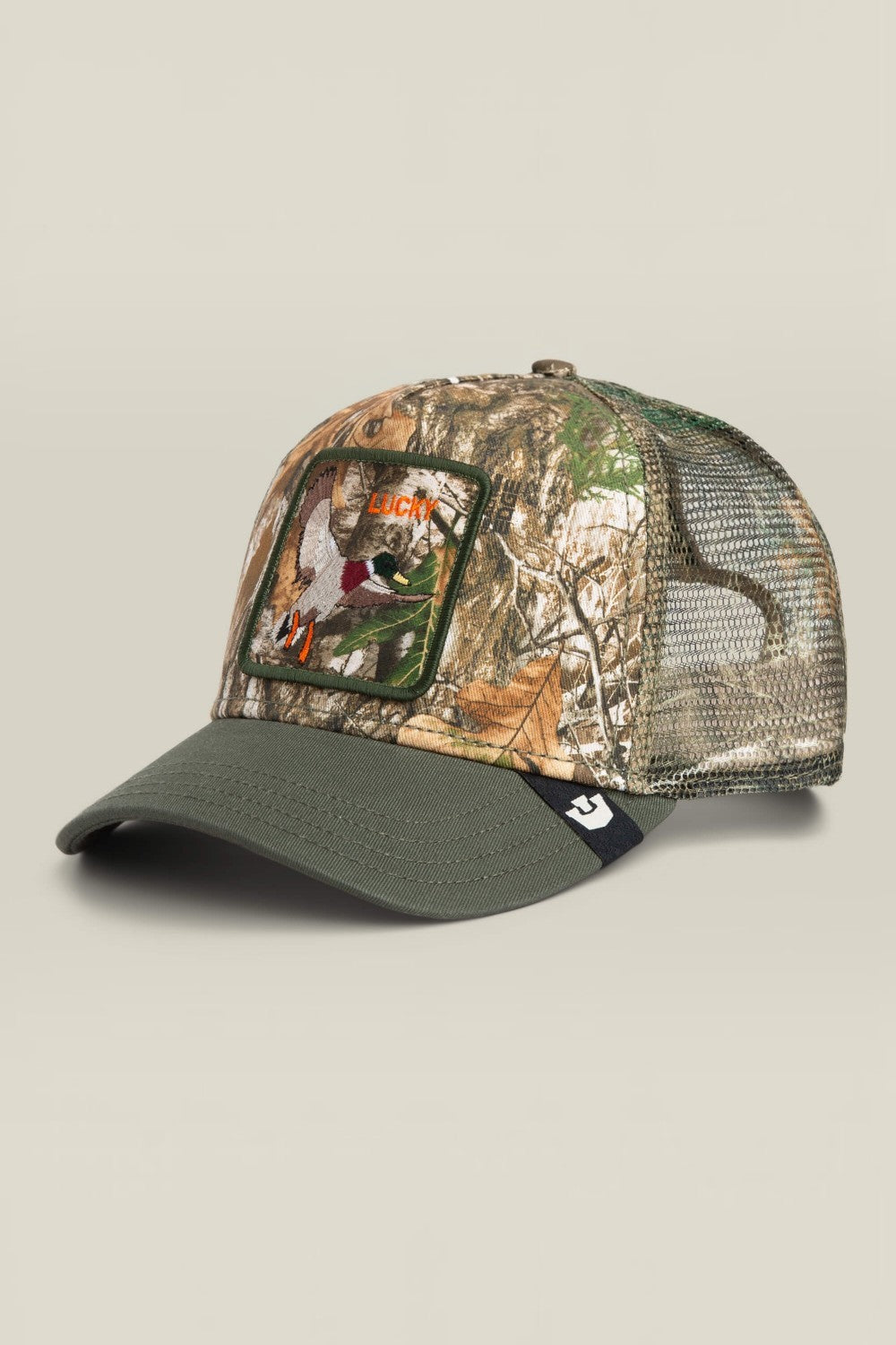 A camouflage trucker cap with an olive green curved brim, mesh back panels, and a front patch featuring a duck hunting scene with the word 'HUNTER'.