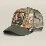 A camouflage trucker cap with an olive green curved brim, mesh back panels, and a front patch featuring a duck hunting scene with the word 'HUNTER'.